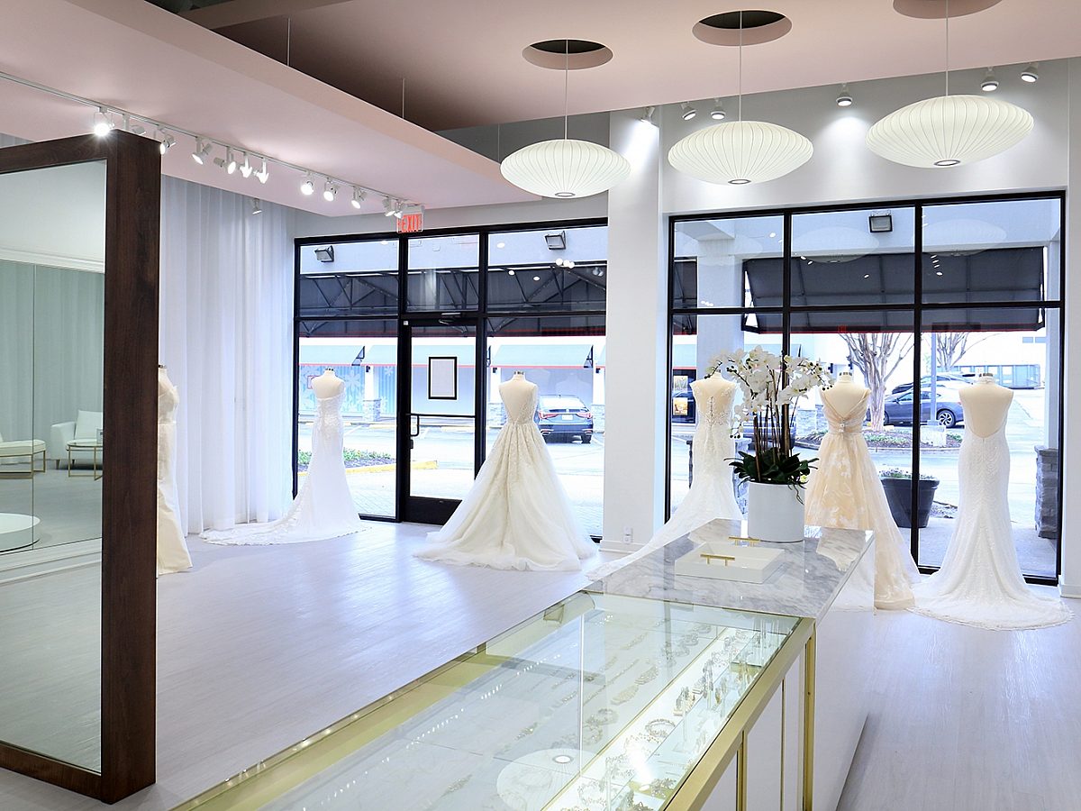 Behind the counter of a bridal boutique with dresses on forms