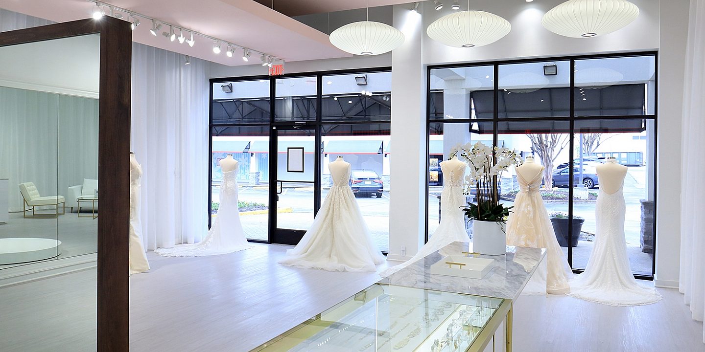 Behind the counter of a bridal boutique with dresses on forms